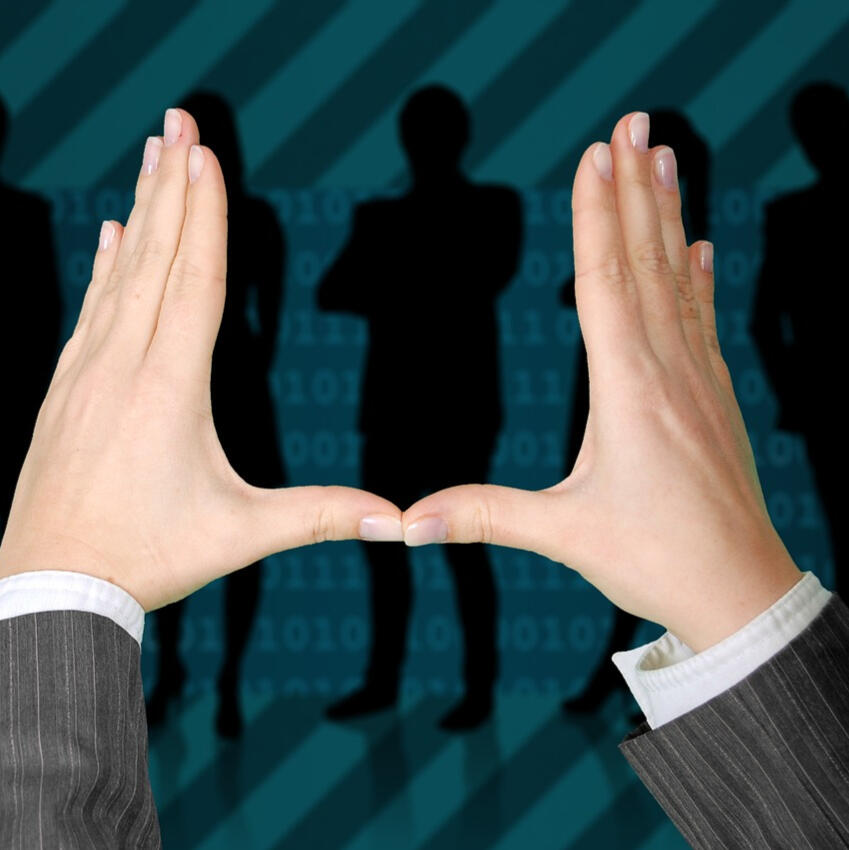 Compliance and Vendor / Software selection. Hands forming a heart shape with business professionals discussing compliance and vendor selection in the background.